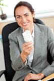 Attractive businesswoman holding a light bulb sitting in her office