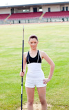 Confident athletic woman ready to throw a javelin standing in a stadium