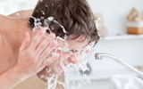 Bright man spraying water on his face after shaving in the bathroom
