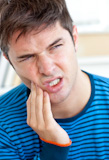 Unhappy man having a toothache in the living-room