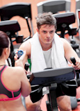 Female coach using a chronometer while man is doing physical exercises in a fitness centre