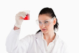 Dark-haired woman looking at a red beaker
