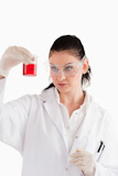 Dark-haired scientist looking at a red beaker