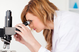 Attractive blonde scientist looking through a microscope