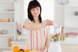 Pretty,brunette,woman,putting,vegetables,in,a,mixer,while,standing