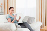 Attractive woman making an online payment with her credit card while sitting on a sofa