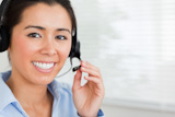 Portrait of a beautiful woman with a headset helping customers while sitting