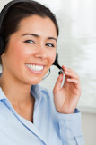 Portrait of a good looking woman with a headset helping customers while sitting
