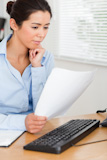 Attractive woman looking at a PC screen while holding a sheet of paper