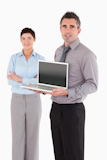Portrait of a man showing a laptop while his colleague is posing