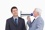 Close up of mature businessman with megaphone yelling at employee