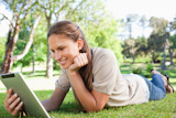 Smiling woman laying on the lawn with her tablet PC