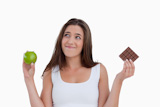 Relaxed,young,woman,holding,an,apple,and,chocolate