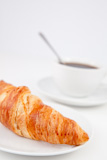 Croissant and a cup of coffee on white plates with sugar and milk