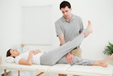 Brunette physiotherapist manipulating the leg of a woman