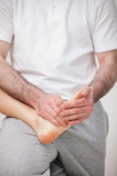 Podiatrist massaging the foot of a woman while holding it on his thigh