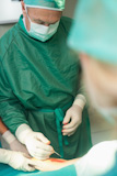 Surgeon taking scissors from a gloved hand