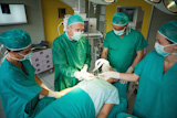 Team of surgeons operating the arm of a patient