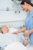 Nurse smiling to a patient while holding her hand