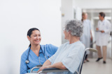 Elderly patient in a wheelchair looking at a nurse
