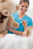 Smiling nurse holding a teddy bear