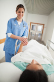 Patient lying on a medical bed holding the hand of a nurse