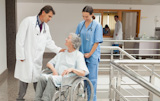 Nurse kneeling beside  old women sitting in wheelchair