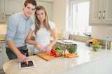 Woman chopping s with man reading cookbook