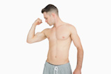 Young shirtless man exercising with dumbbell