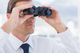 Businessman using binoculars in front of the camera