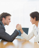 Business couple arm wrestling of an office desk