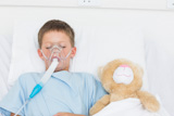 The boy is wearing the oxygen mask idle near the stuffed animal.