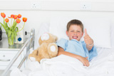 The boy expresses the thumb with the teddy bear of a hospital by gesture.