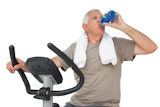 Senior-man drinking water on an exercise bicycle