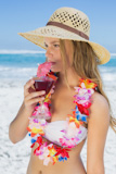 Pretty blonde in floral garland sipping cocktail on the beach