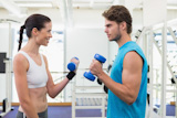 Fit smiling couple exercising with blue dumbbells