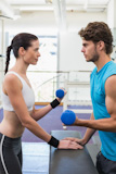 Fit focused couple exercising with blue dumbbells