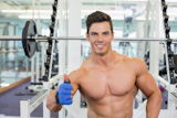 Smiling shirtless muscular man giving thumbs up in gym