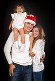 Father in santa hat holding little girl on his shoulder and hugged his wife